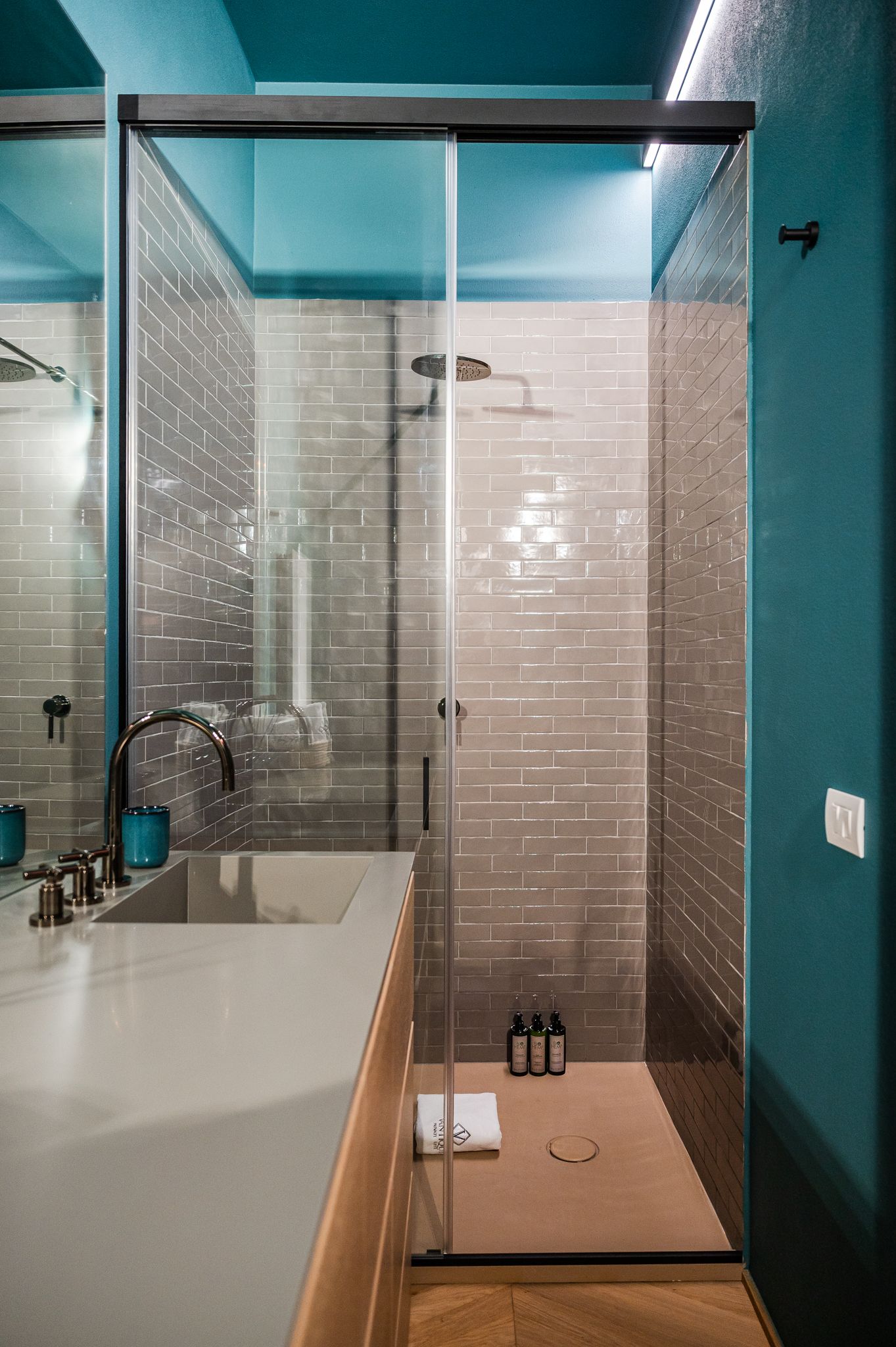 Doccia del bagno turchese con piastrelle subway grigie e soffione a pioggia