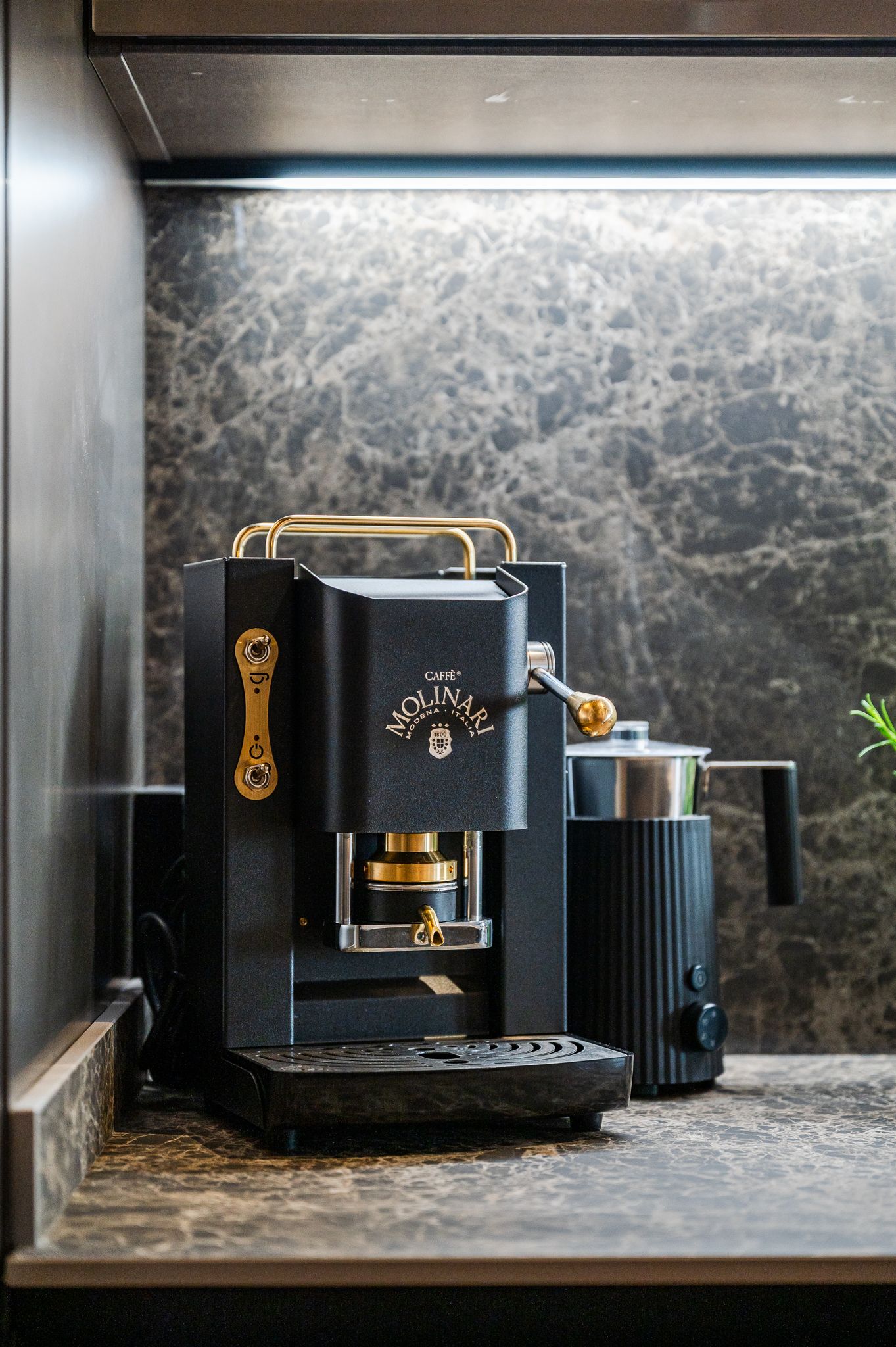 Dettaglio della macchina da caffè Molinari in cucina con vaso di rosmarino