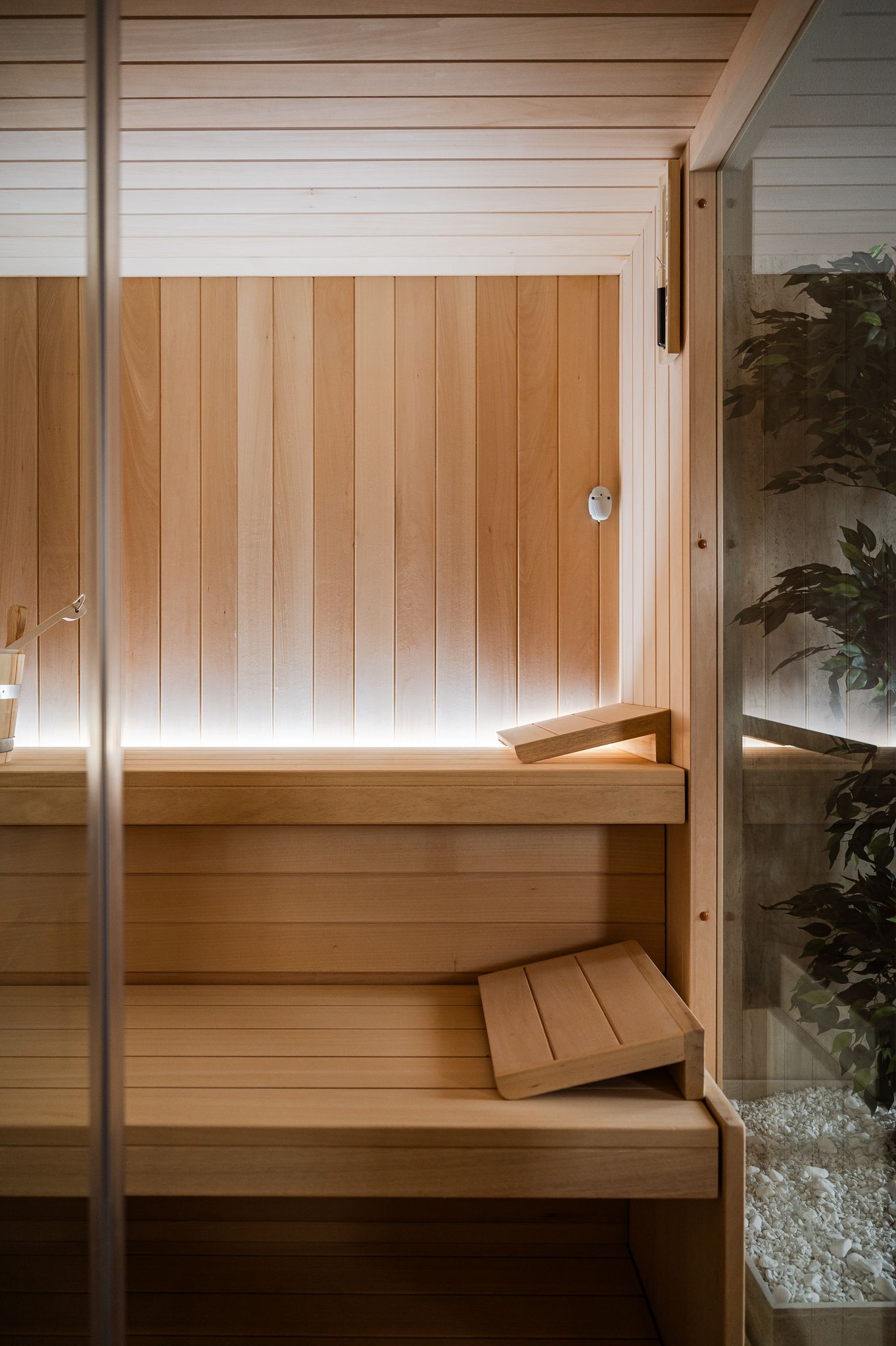Interno della cabina sauna con schienali in legno chiaro e parete in vetro